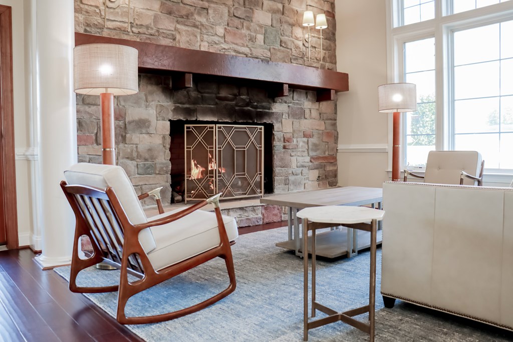 a living room with a fireplace and a table and chairs at Broadlands Apartments in Ashburn, VA 20148